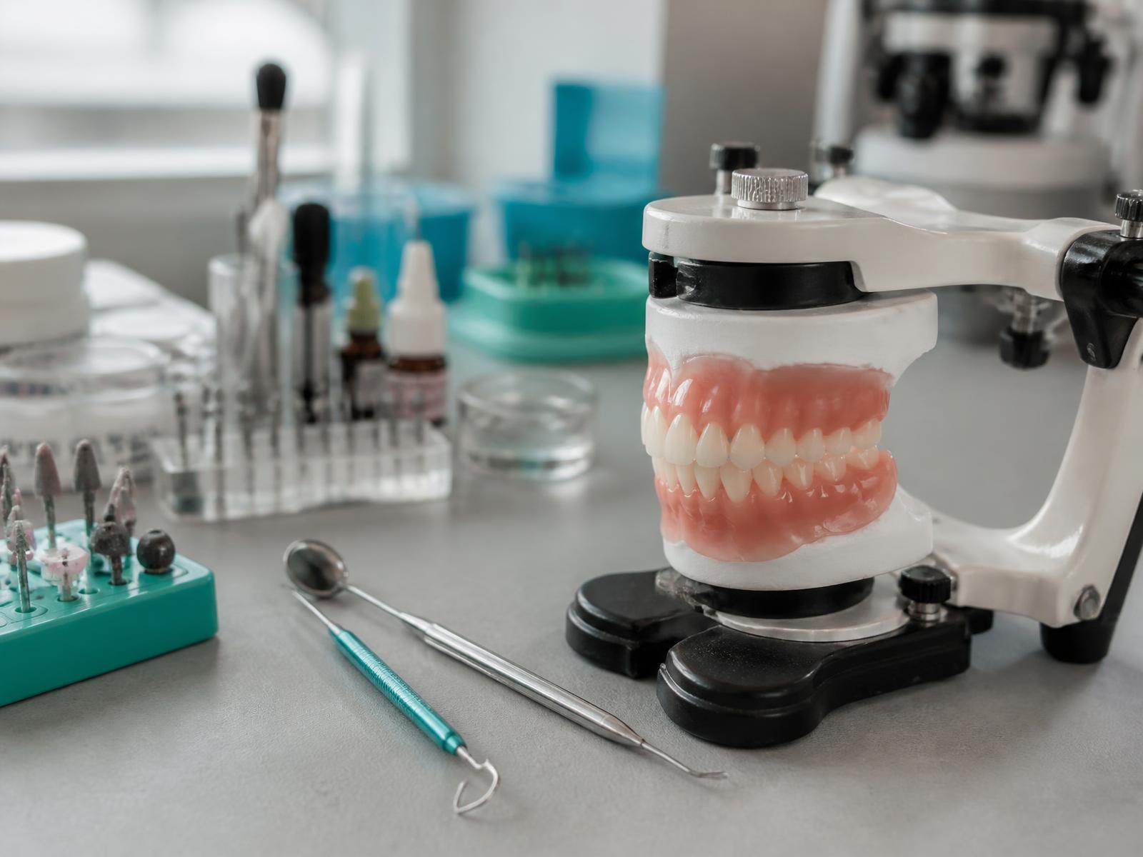Dental laboratory bench with precision tools and a custom denture on an articulator